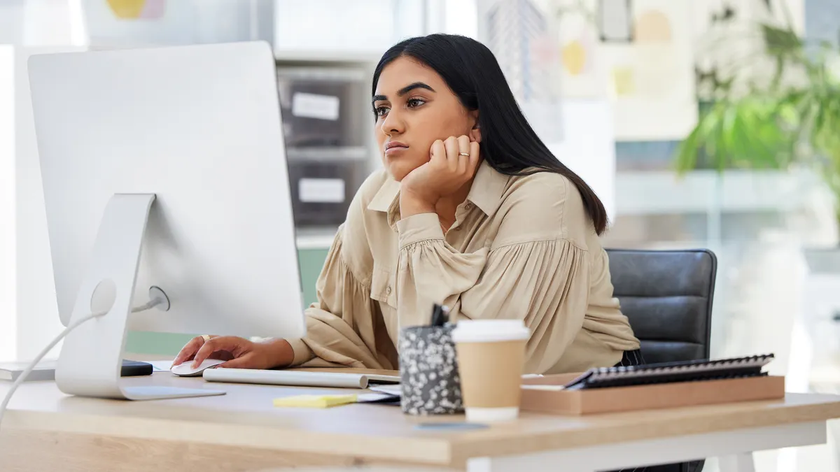 Dipendente stanco che lavora su un computer in ufficio appoggiato