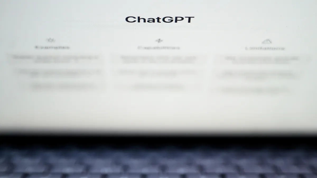 Lo schermo di un laptop mostra la parola "ChatGPT" e tre colonne di testo sfocato